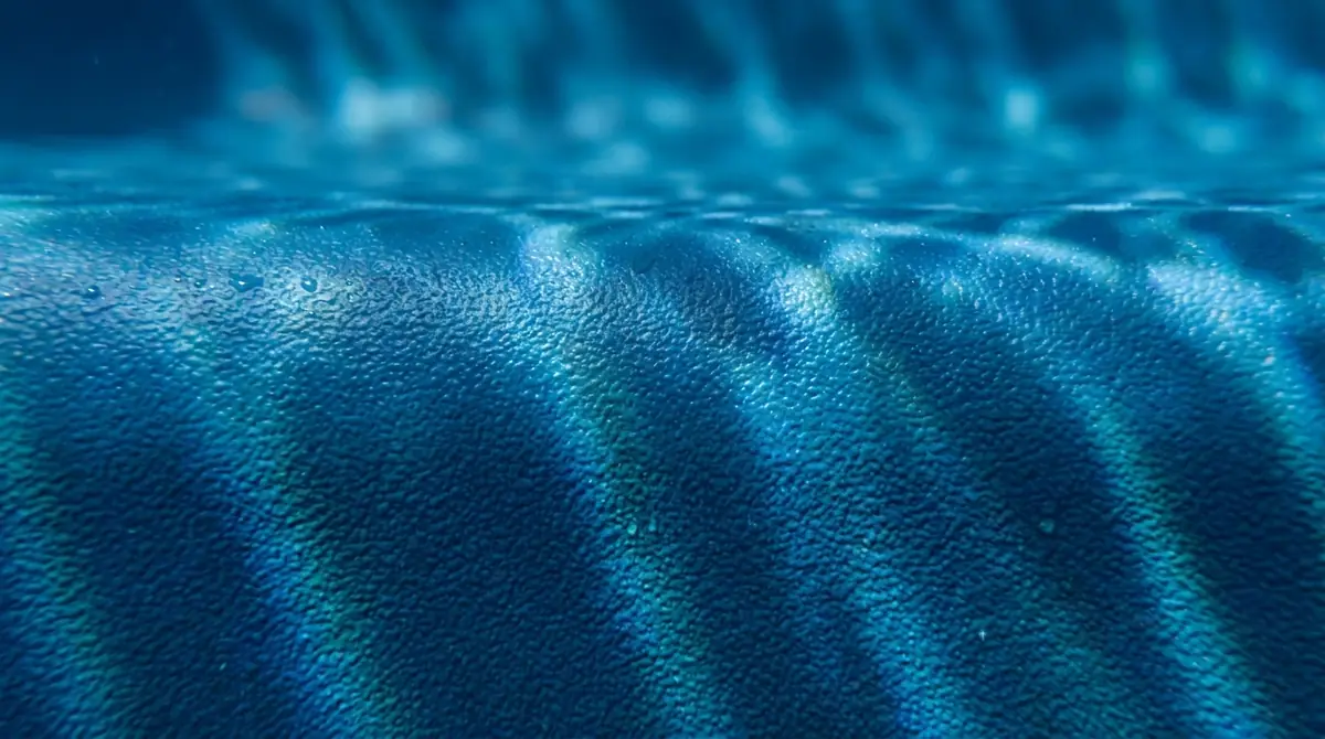 Close-up of an ecoFINISH pool surface underwater showing the fine orange-peel texture and even color of the heat-fused coating.