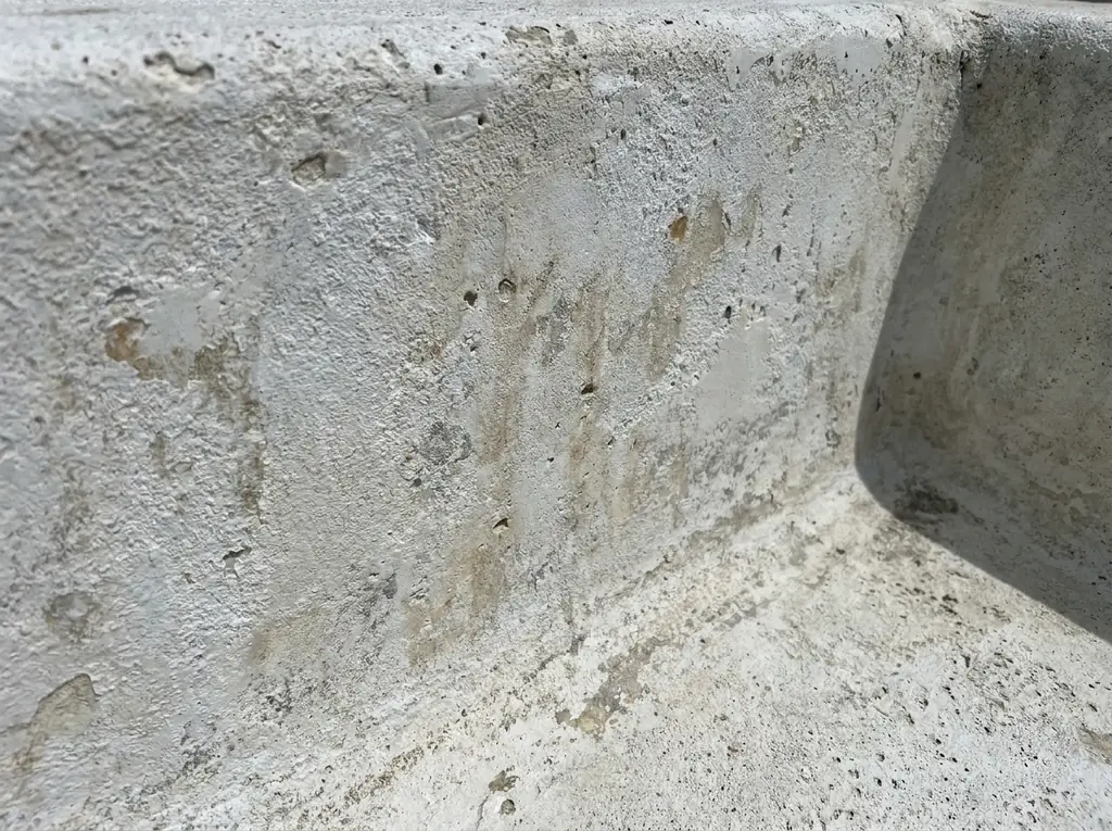 Close-up of an aging, chalky pool surface with faint staining, showing a pool due for resurfacing.